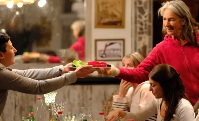 Grace reicht bei einem gemeinsamen Abendessen einen Teller