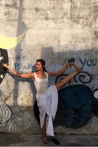 Grace in Yoga-Pose vor einer Wand mit Streetart