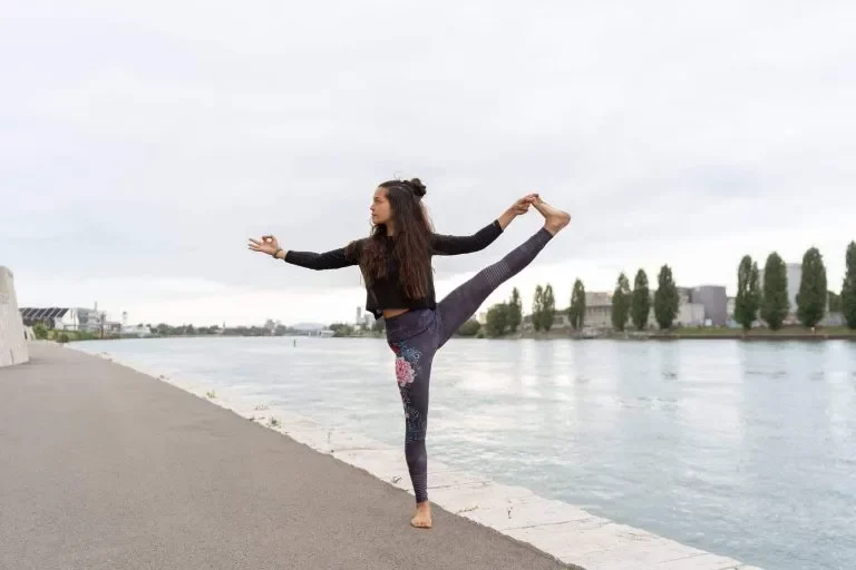 Grace in Yoga-Balancehaltung am Flussufer