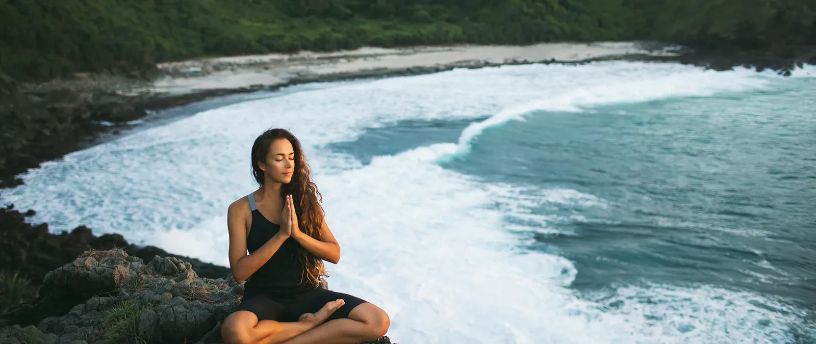 Stefanie Grace in Meditationshaltung an einer Steilküste