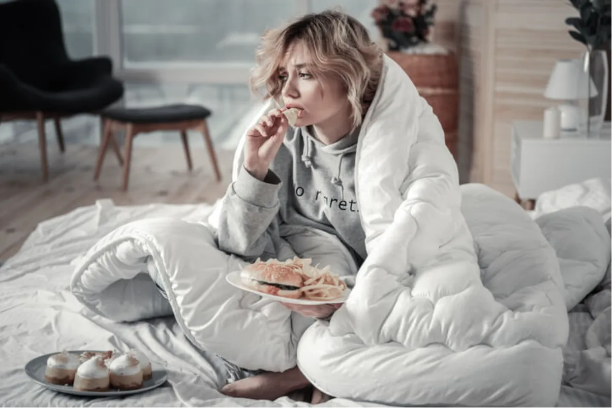 Frau isst Chips im Bett